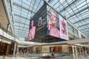 Transparent LED screen displaying advertising visuals in a shopping mall atrium